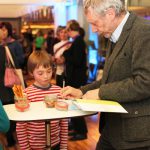 Michael Rosen signs a copy of We're Going on a Bear Hunt for a young fan